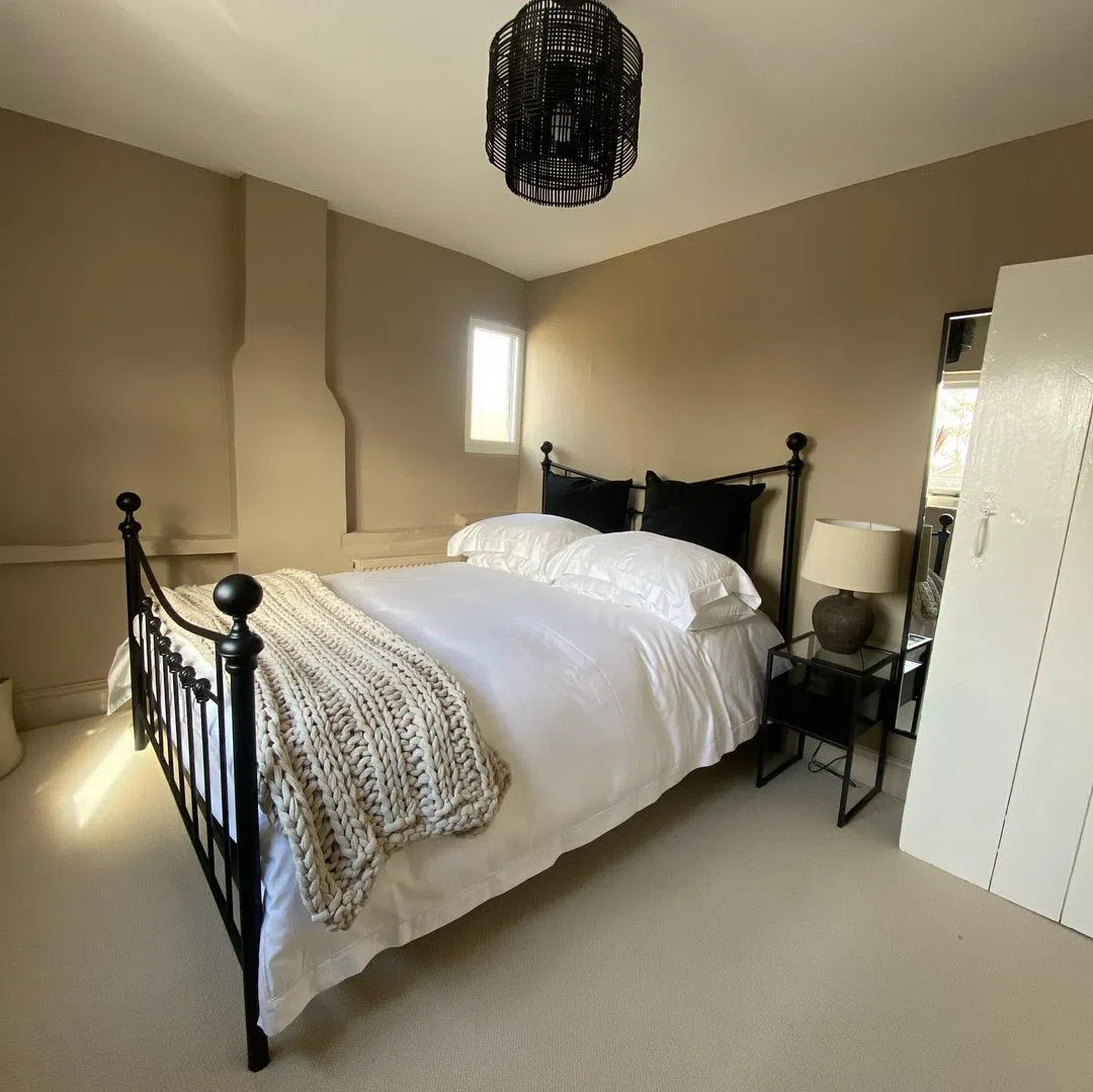 Бежевая спальная с черной кроватью и черной люстрой