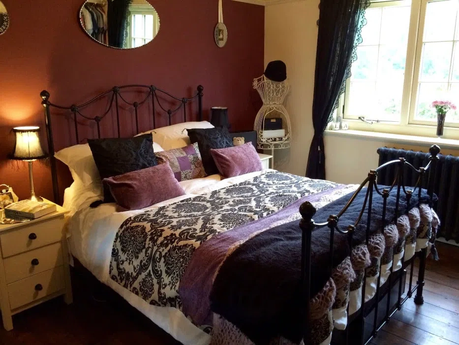 Спальная с кроватью с металлическим основанием и красной стеной