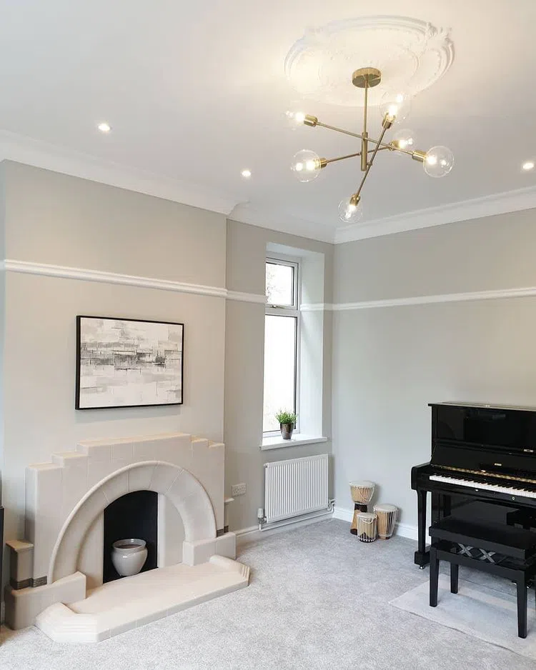 Гостиная с камином с люстрой цвета латуни и серыми стенами