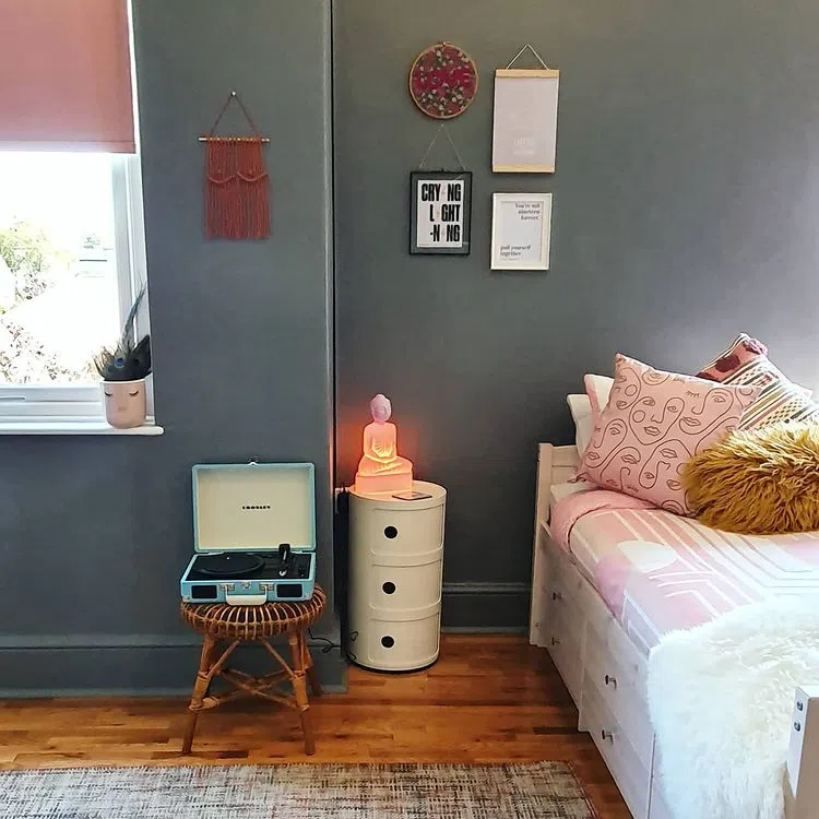 Круглая белая прикроватная тумбочка с полками и серые стены