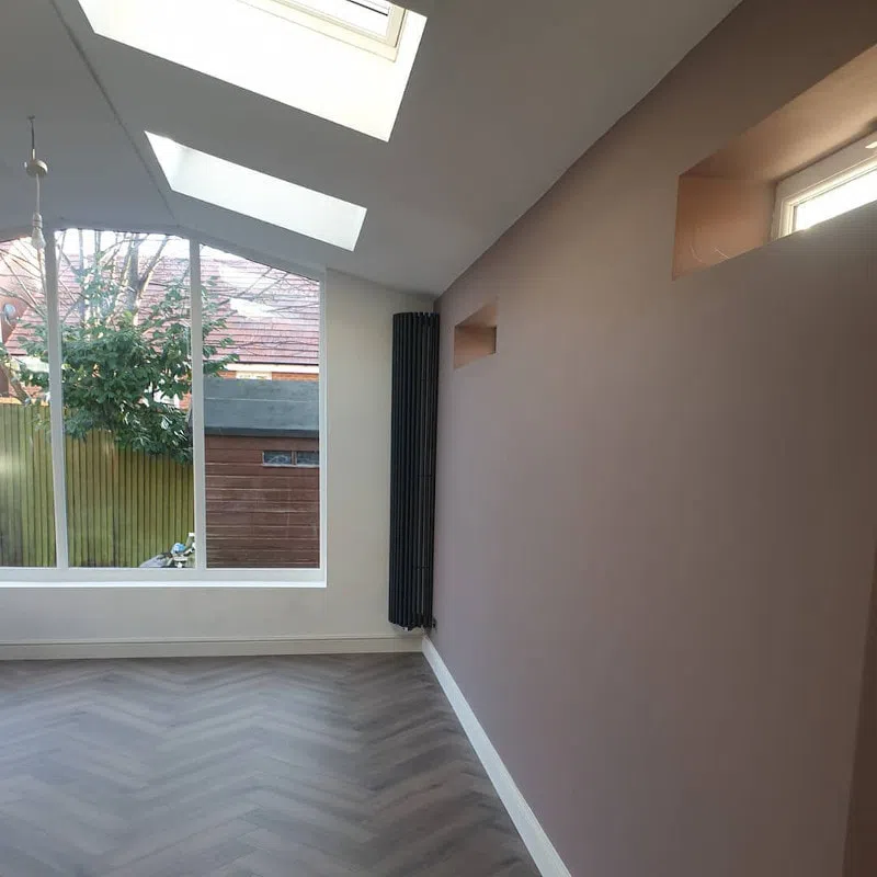 Акцентная розовая стена в гостиной с черными радиаторами