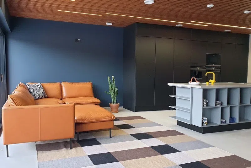 Интерьер с синими стенами ral 5008 и рыжим кожаным диваном